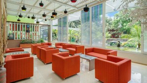 Un espacio interior amplio con asientos naranja, ventanas grandes y un techo con luces colgantes.
