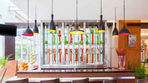 Un área de bar con diseño moderno, que incluye un separador de vidrio con botellas y copas, además de taburetes de bar.
