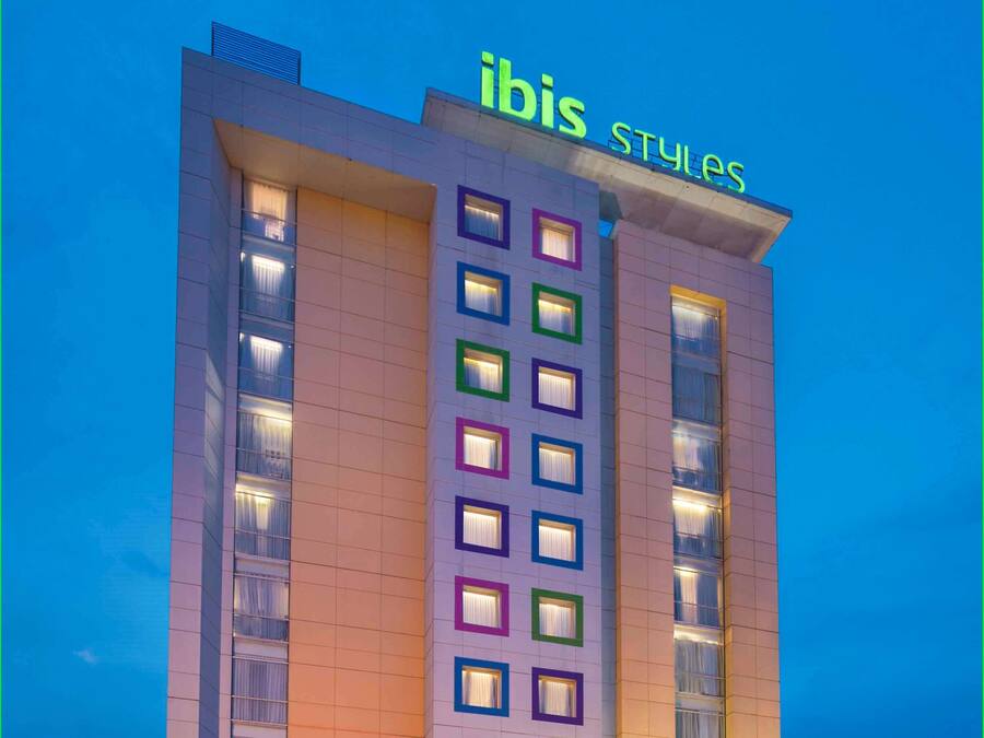 Un edificio con un letrero que dice "ibis Styles" y varias ventanas con marcos de colores.