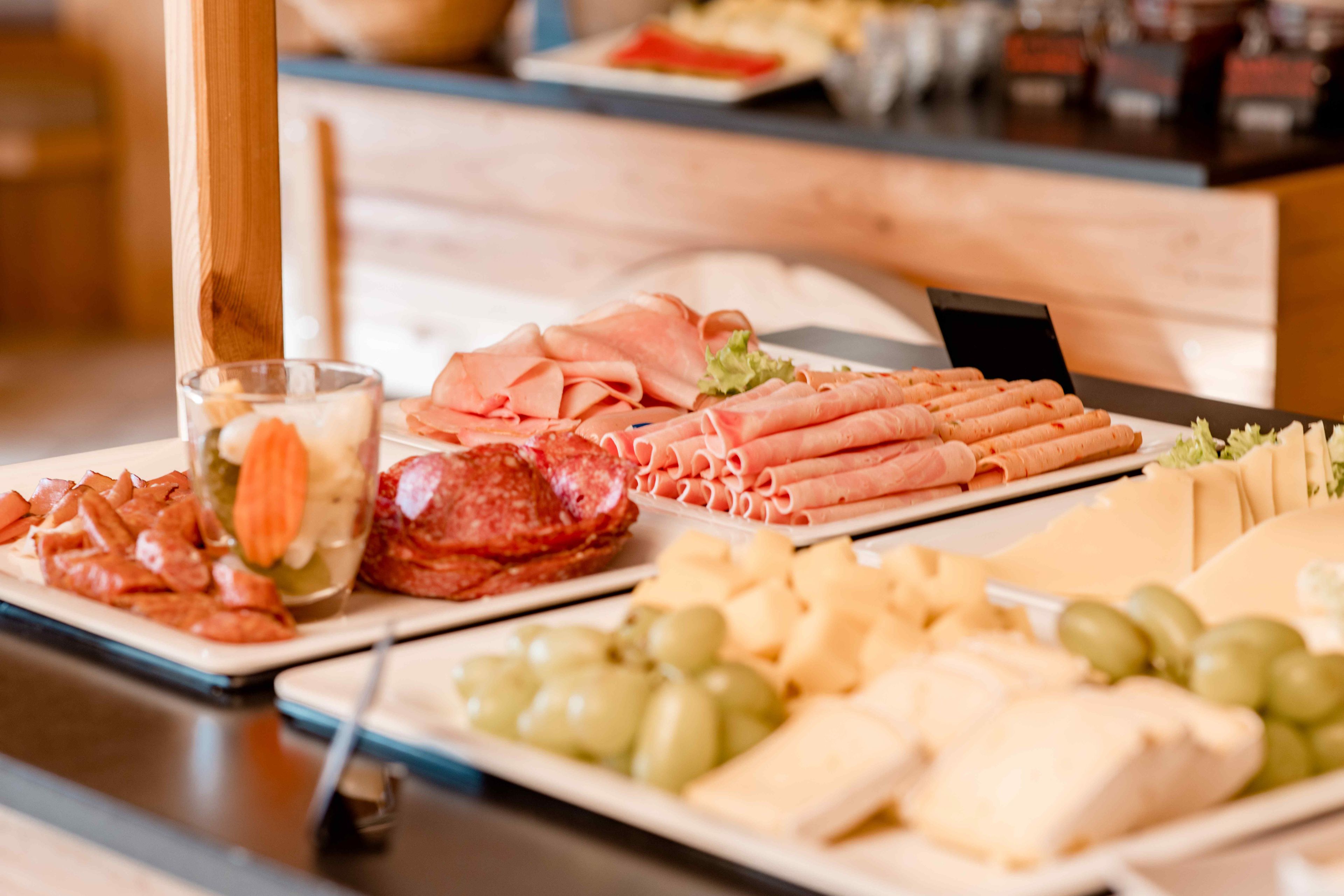 Verschiedene Speisen, darunter Fleisch, Käse und Gemüse, ansprechend auf Tellern angerichtet.