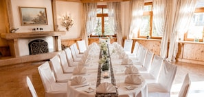 Una larga mesa de comedor dispuesta para un evento formal, con manteles blancos, sillas y centros de mesa.