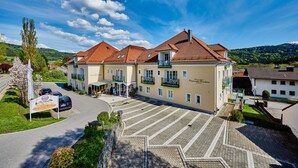 A hotel with a tiled roof, multiple balconies, and a paved courtyard.