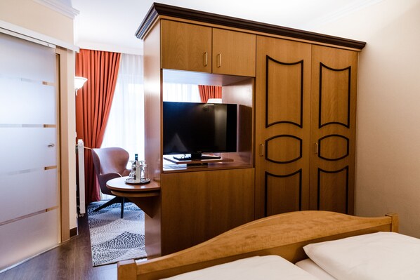 Een hotelkamer met een bed, een bureau met een computer, een televisie en een kledingkast.