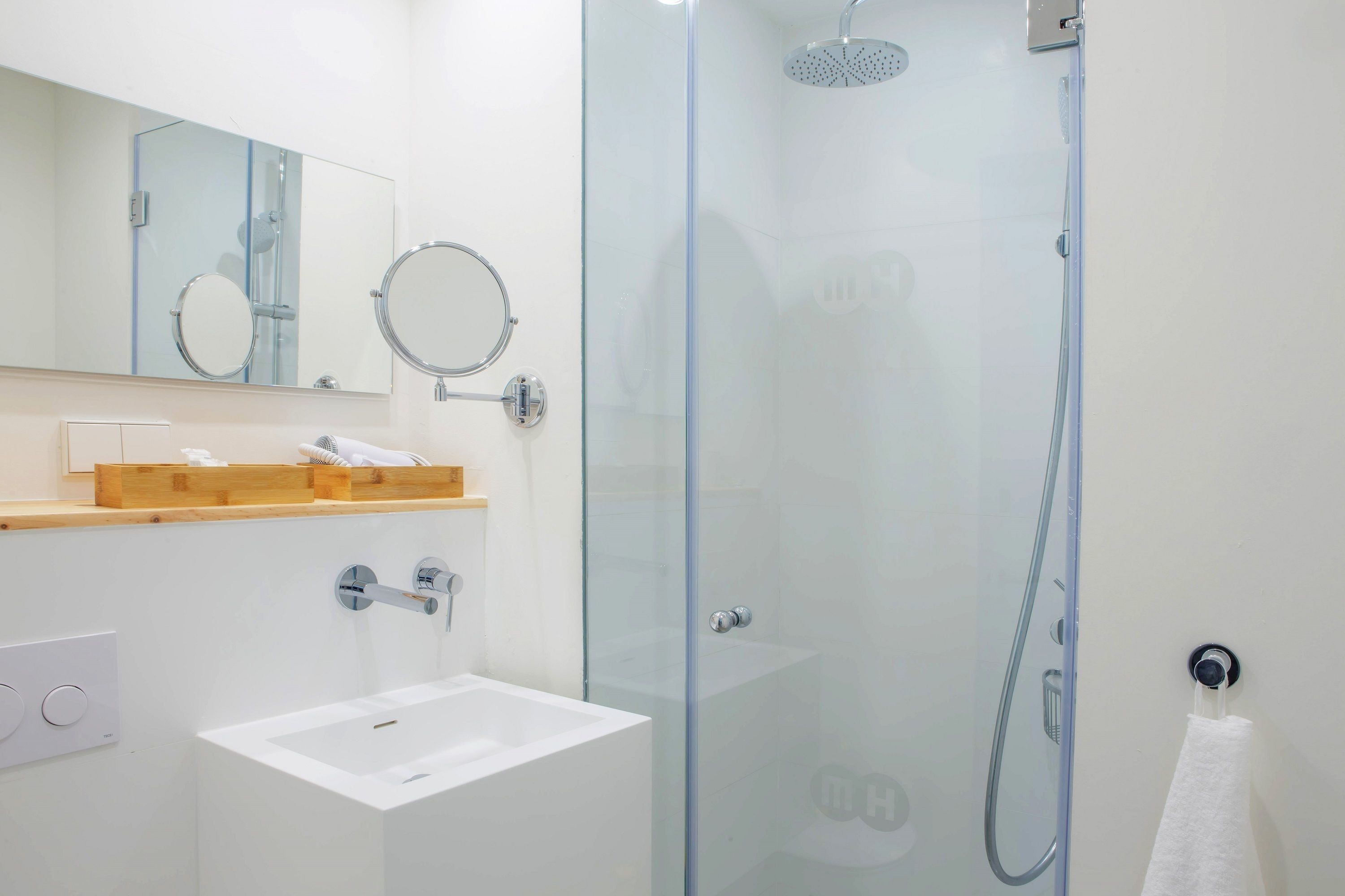 A modern bathroom with a glass-enclosed shower, a white sink, and a mirror above the sink.
