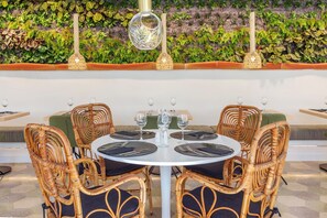 Una mesa redonda con sillas, rodeada por un exuberante muro verde con plantas.