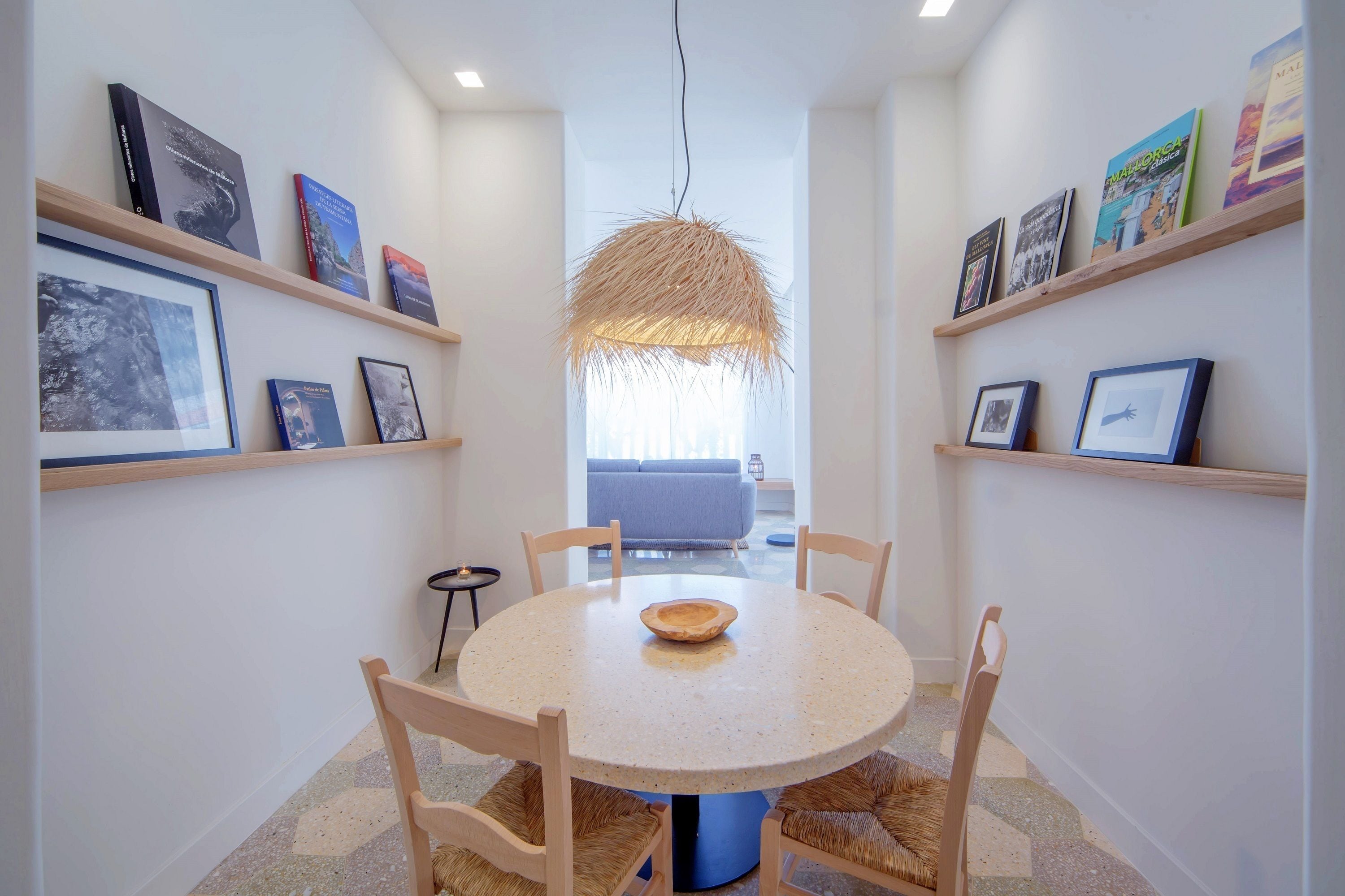 A dining area with a round table, chairs, and a hanging light fixture.