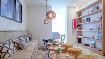 Una sala de estar moderna con un sofá, mesas redondas de madera, sillas de mimbre y una estantería.