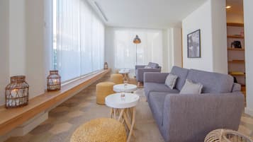A modern living room with a grey sofa, round wicker ottomans, and a white coffee table.