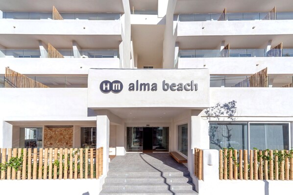 A modern hotel entrance with a staircase leading to the lobby, a sign reading "alma beach," and a bamboo fence. - Hotel HM Alma Beach - Adults Only (Palma de Mallorca)