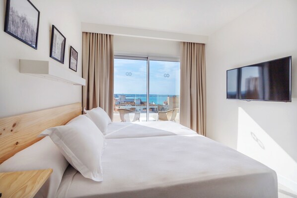 A hotel room with a large bed, a TV mounted on the wall, and a balcony with a view of the sea. - Hotel HM Alma Beach - Adults Only (Palma de Mallorca)