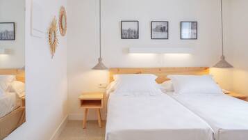 A hotel room with two single beds, a wooden headboard, bedside tables, and wall-mounted artwork.