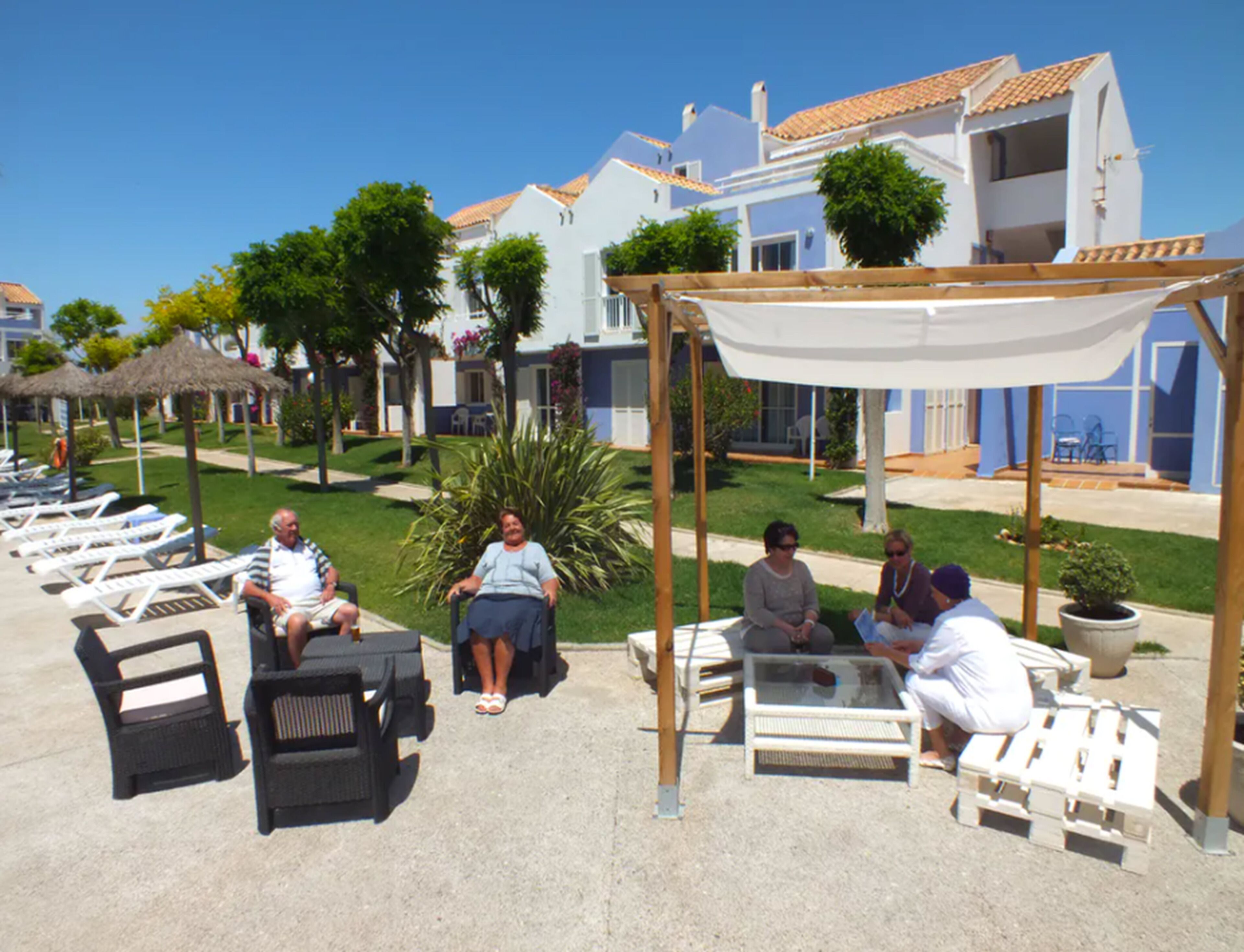 A resort with outdoor seating areas, palm trees, and a clear blue sky.