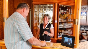 A bar area with a bartender, a counter, and a display screen. - Akzent City Hotel Kleve (Kleve)