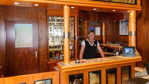 A bar area with wooden decor, a bartender, and a menu board. - Akzent City Hotel Kleve (Kleve)