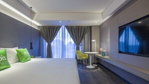Une chambre d’hôtel moderne avec un grand lit, une télévision, une petite table et une chaise.