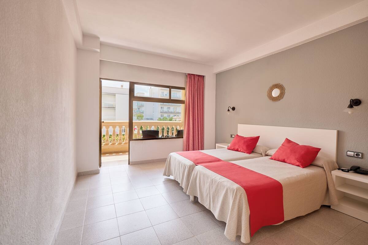 Quarto de hotel com duas camas, varanda e vista, e design moderno.