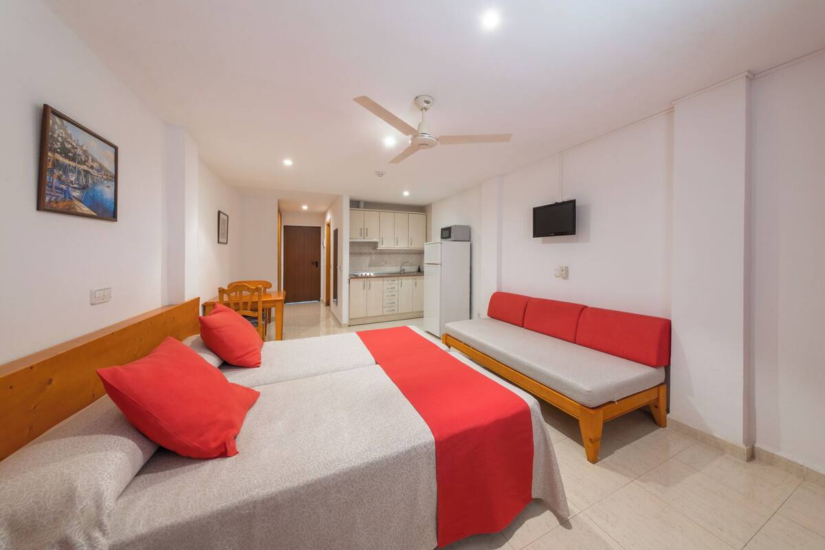 Quarto de hotel com duas camas, um sofá, uma mesa de jantar e uma cozinha.