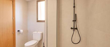 A bathroom with a toilet, a shower, and a wooden door.