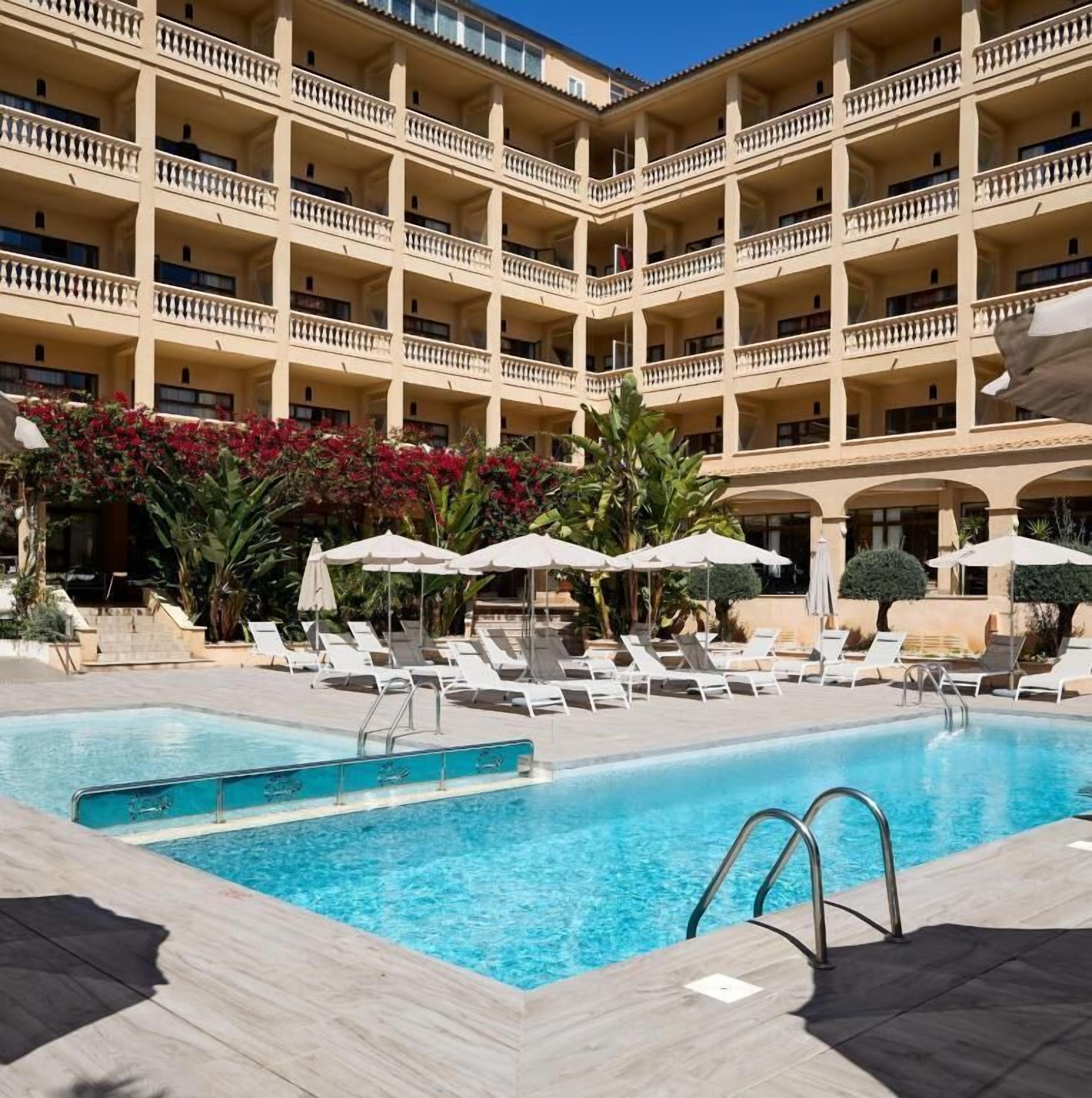 Ein Hotel mit Poolbereich, mehreren Balkonen und Liegestühlen.