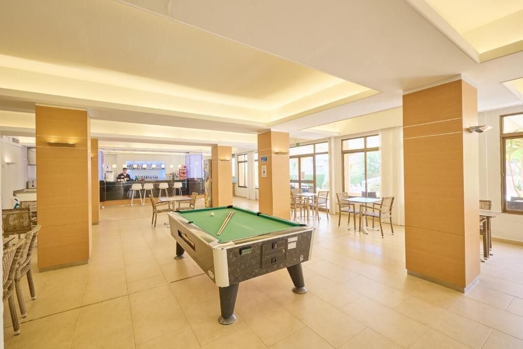 A pool table in a well-lit indoor area with a bar and seating in the background.
