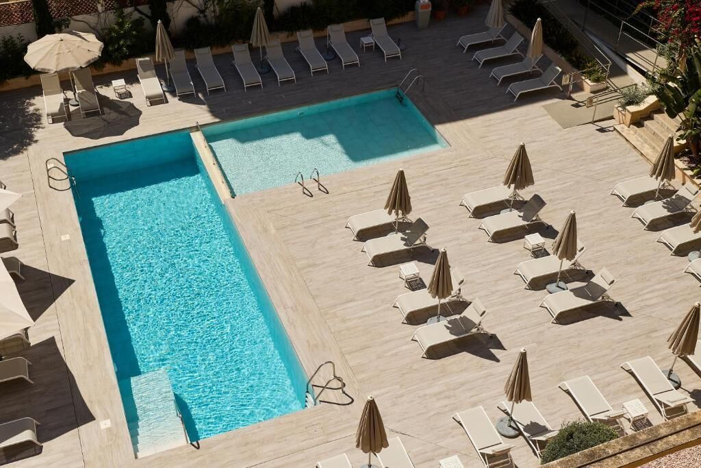 Zona de piscina al terrat amb diversos gandules i para-sols, envoltada per una terrassa de fusta.