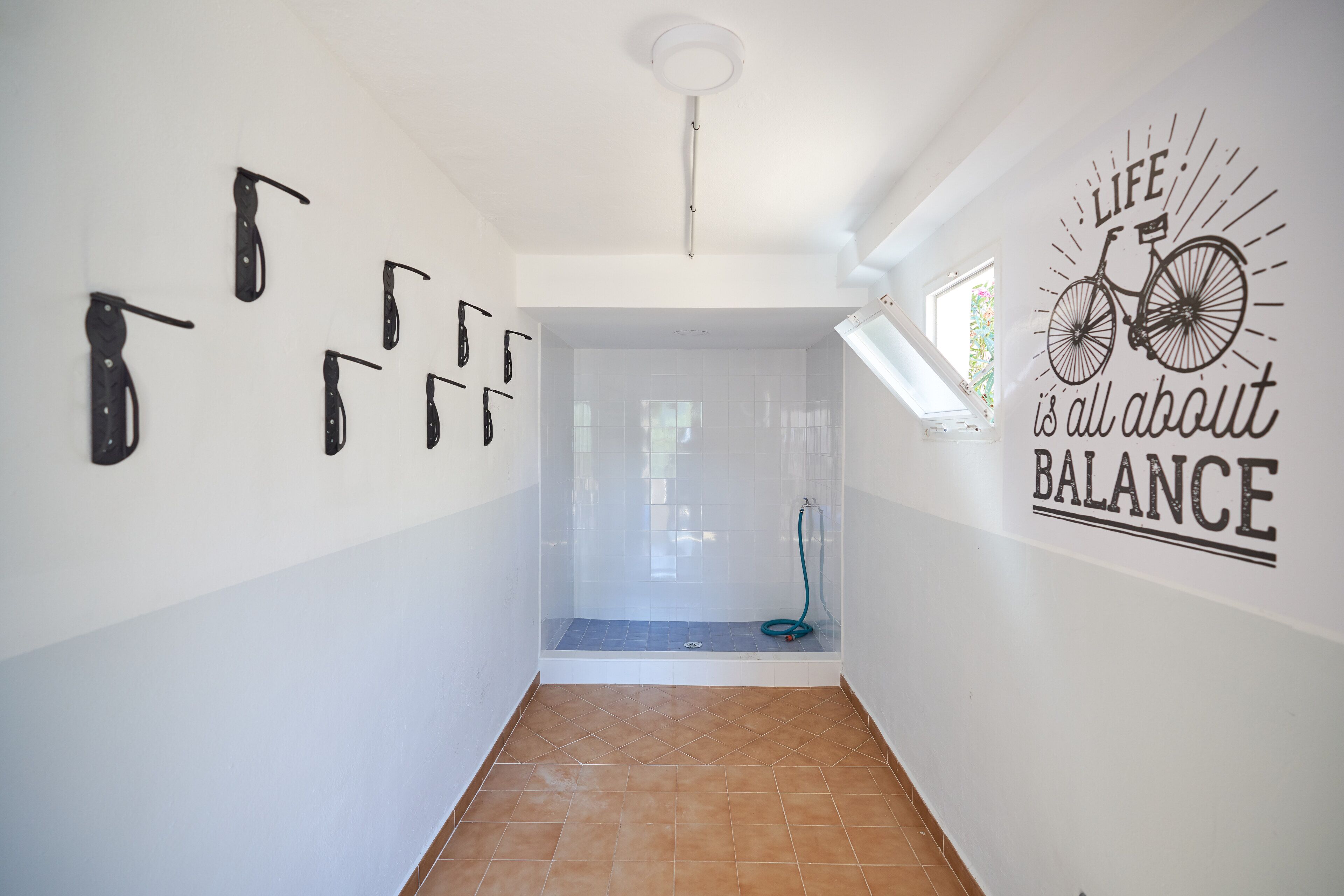 Un pasillo con ducha, una pared con cuchillos y una cita motivacional sobre equilibrio.