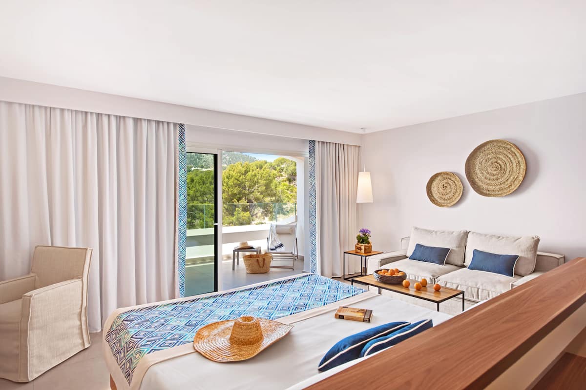 Een hotelkamer met een bed, een slaapbank, een eettafel en uitzicht op de omgeving.
