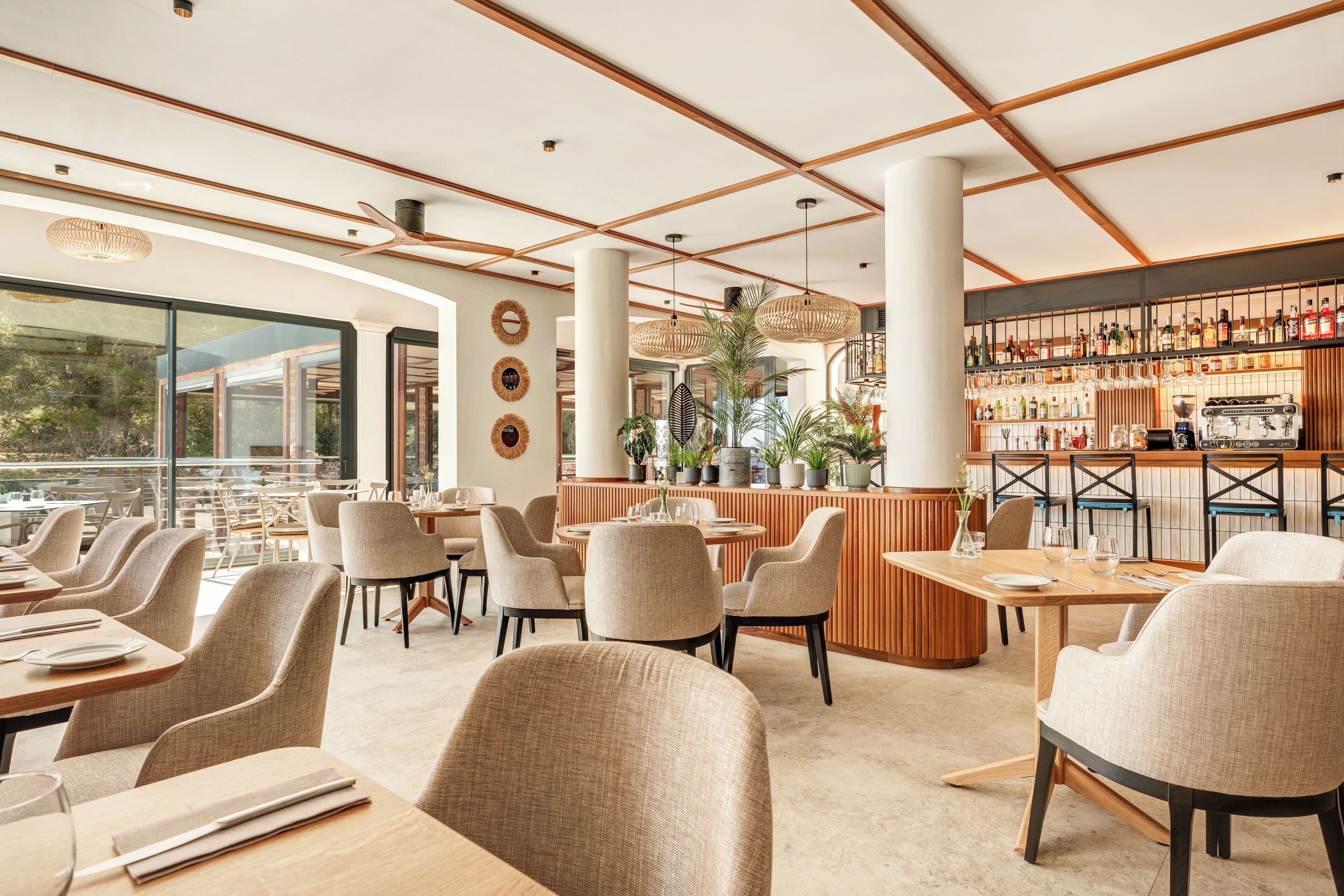 Un restaurant moderne avec de hauts plafonds, de grandes fenêtres et un bar bien fourni.