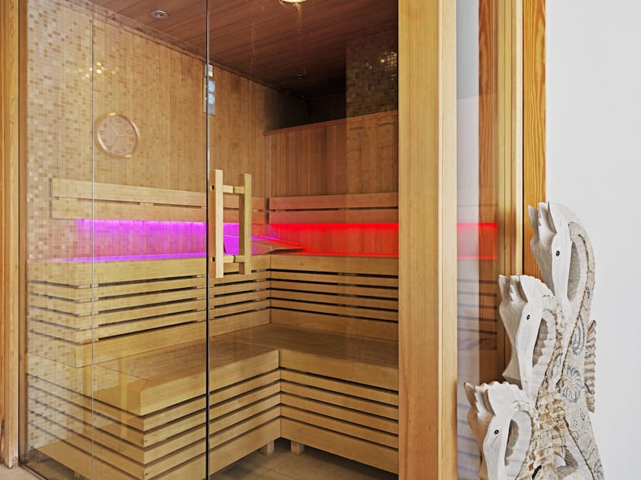 Una sauna con bancos de madera y puerta de vidrio, que incluye un reloj y un adorno en la pared.