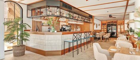 A modern bar area with a curved counter, bar stools, and a ceiling fan.