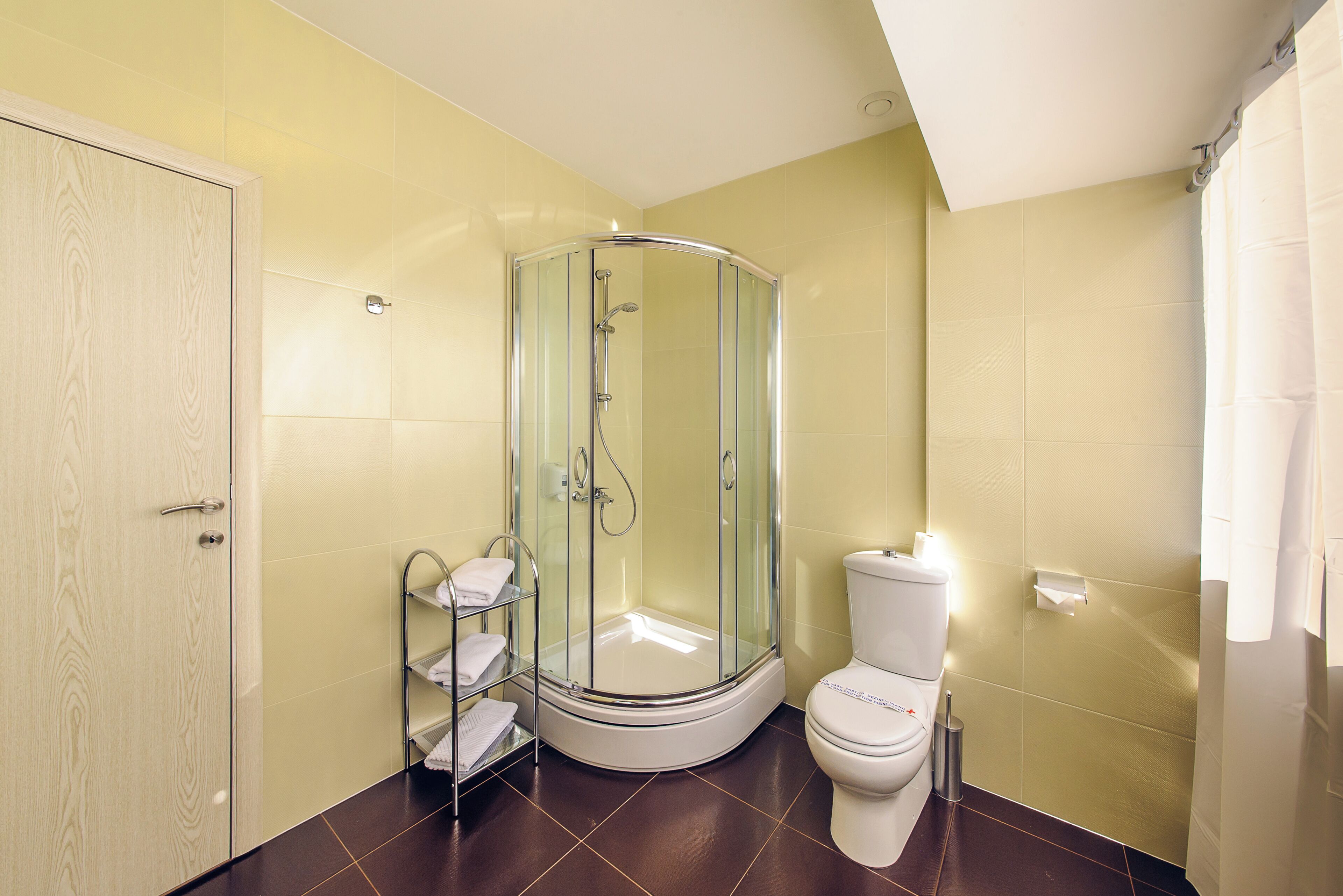 A bathroom with a glass-enclosed shower, a toilet, and a wooden door.