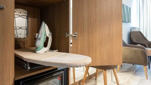 A room with a wooden wardrobe, an ironing board, and a mini-fridge containing beverages. - Hotel Klassik Berlin (Berlin)