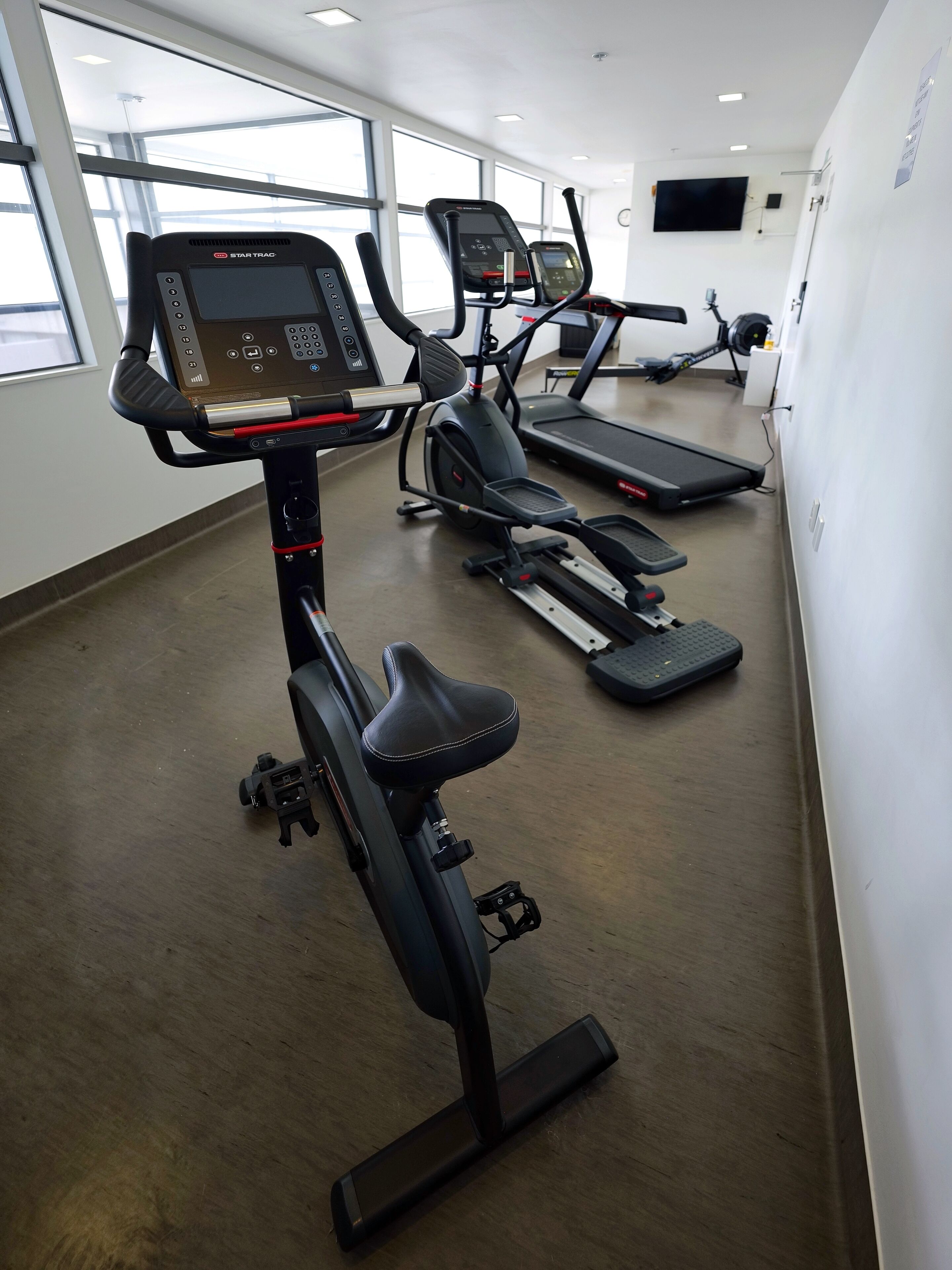 A gym with stationary bikes, treadmills, and a large window.