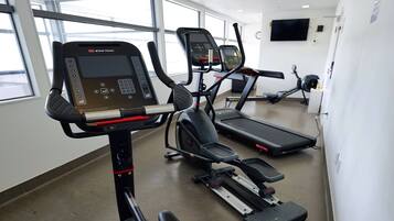 A gym with stationary bikes, treadmills, and a large window.