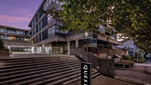 A modern building with a staircase leading to an entrance labeled "QUEST". - Quest Parnell (Auckland)