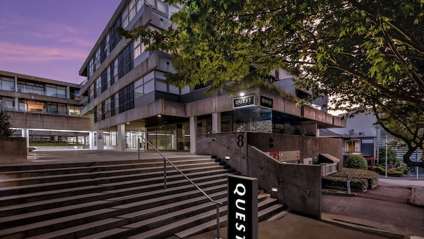 A modern building with a staircase leading to an entrance labeled "QUEST". - Quest Parnell (Auckland)