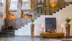 A staircase with a wrought iron railing, leading to a landing with a wooden bench and two floor lamps. - Santa Teresa Hotel Rio de Janeiro - MGallery Collection (Rio de Janeiro)