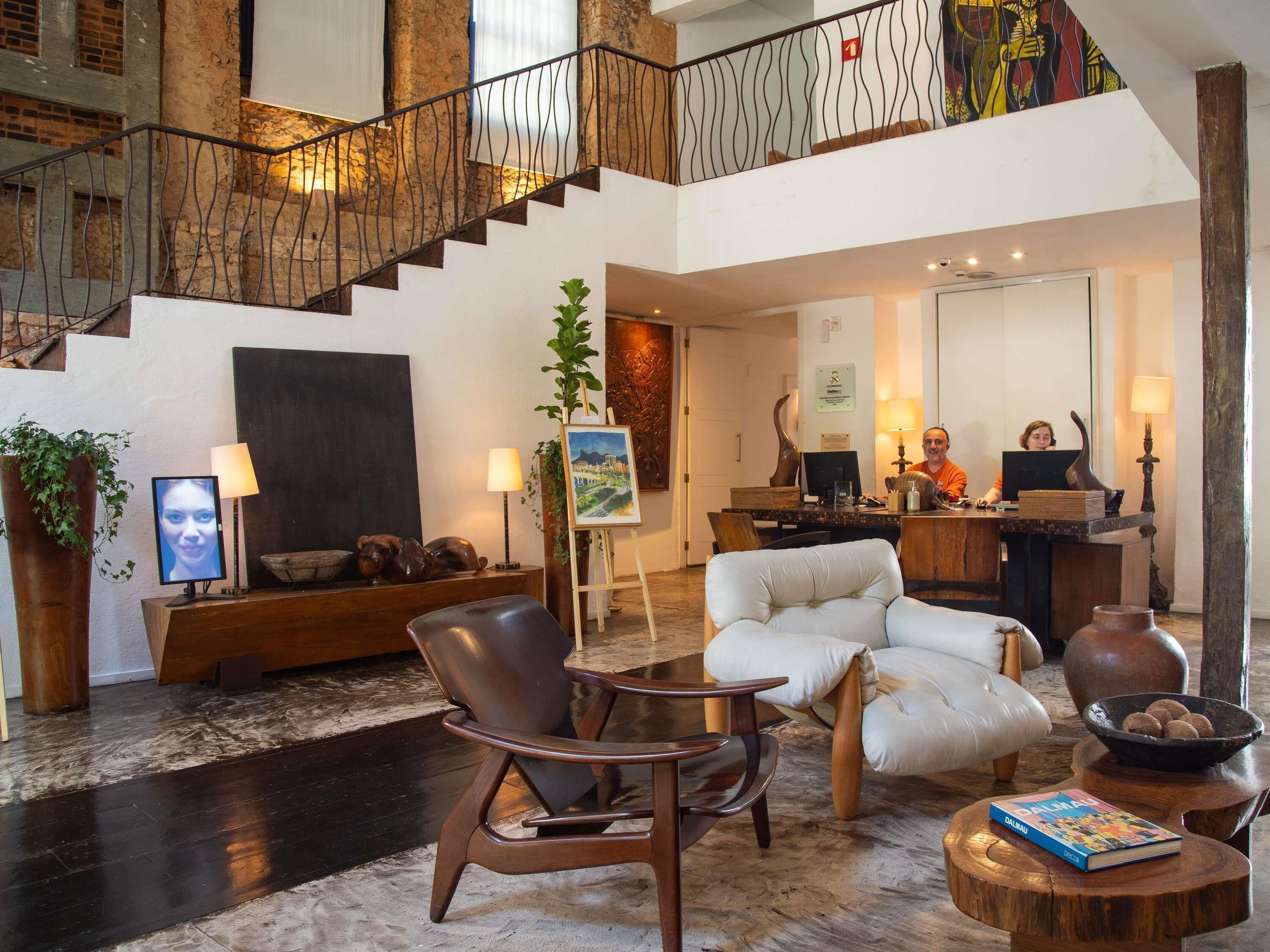 A spacious lobby with a staircase, seating area, and a reception desk.