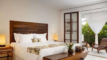 A bedroom with a wooden headboard, a bed with white linens, a bedside table with a lamp, and a view of the outdoors through a glass door.