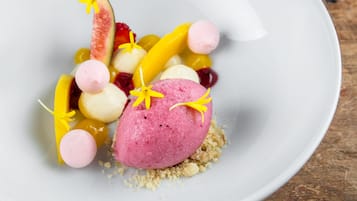 Un plato de postre con diversas frutas y una porción de helado rosa.
