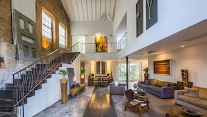 A spacious living area with a high ceiling, a staircase, and a balcony. - Santa Teresa Hotel Rio de Janeiro - MGallery Collection (Rio de Janeiro)