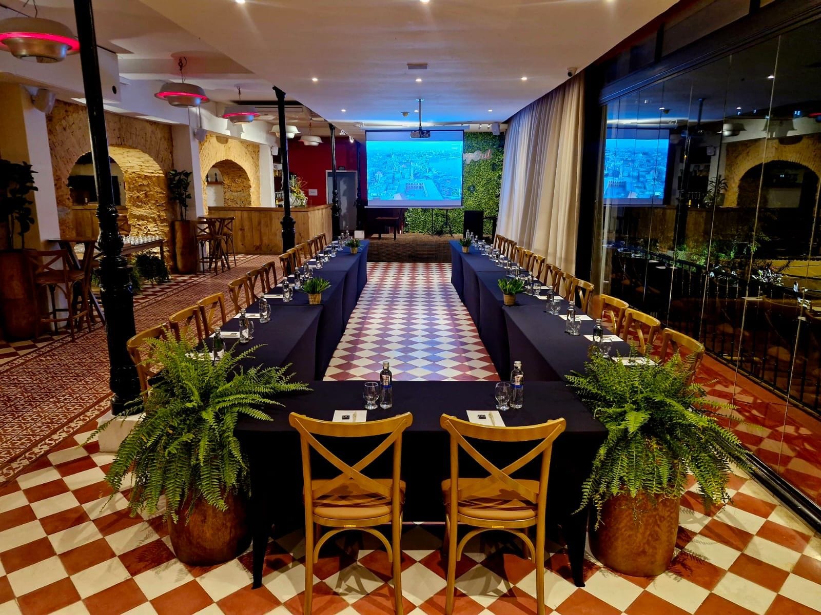 A conference room with a long table, chairs, and a projection screen.