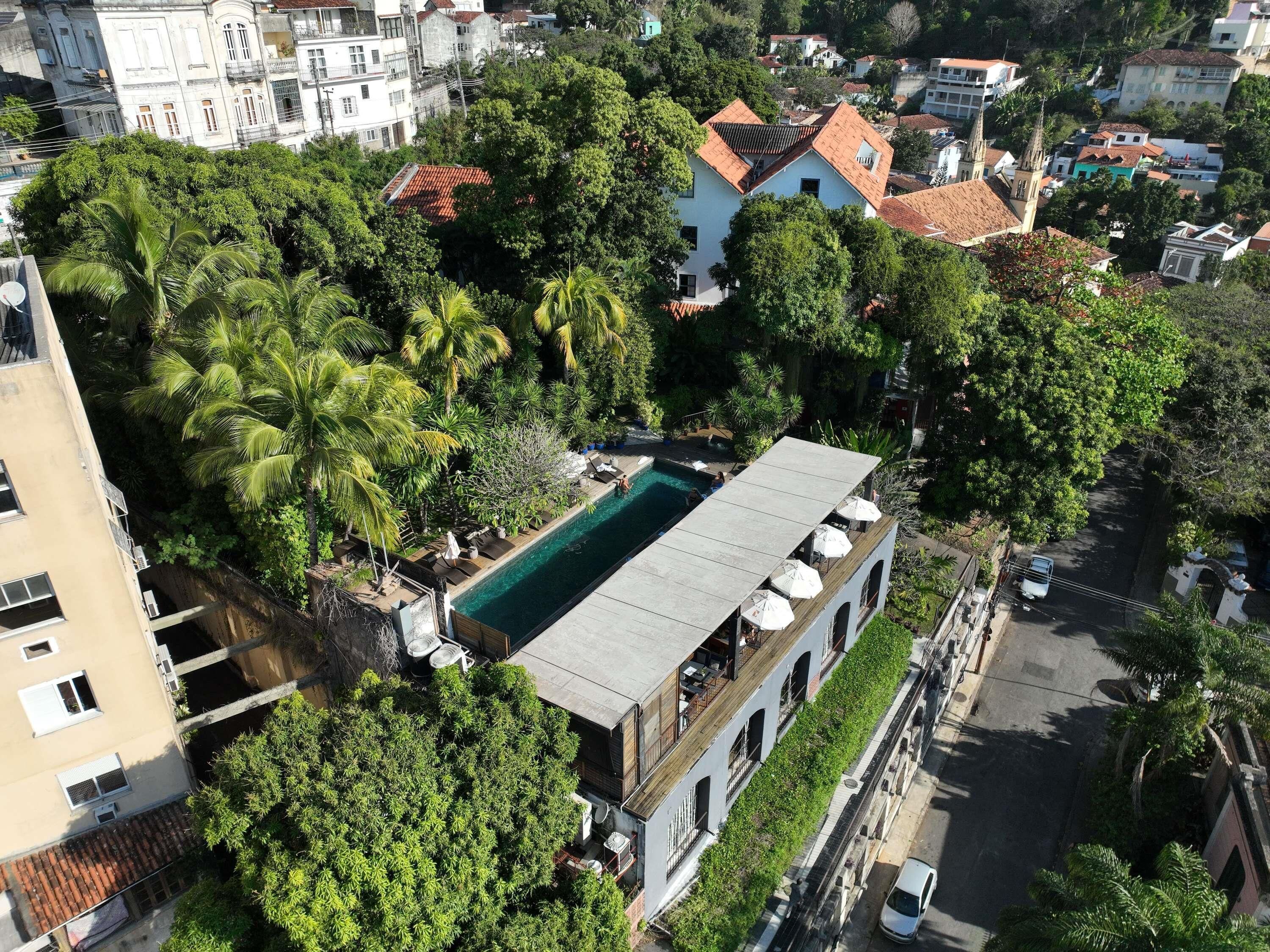 A residential building with a swimming pool, surrounded by lush greenery and adjacent to a street.