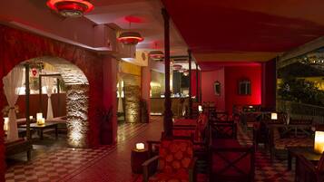 A dimly lit interior with checkered flooring, wooden furniture, and red ambient lighting.