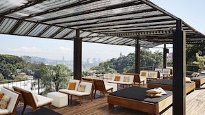 A rooftop terrace with wooden flooring, lounge chairs, and a pergola with patterned fabric. - Santa Teresa Hotel Rio de Janeiro - MGallery Collection (Rio de Janeiro)
