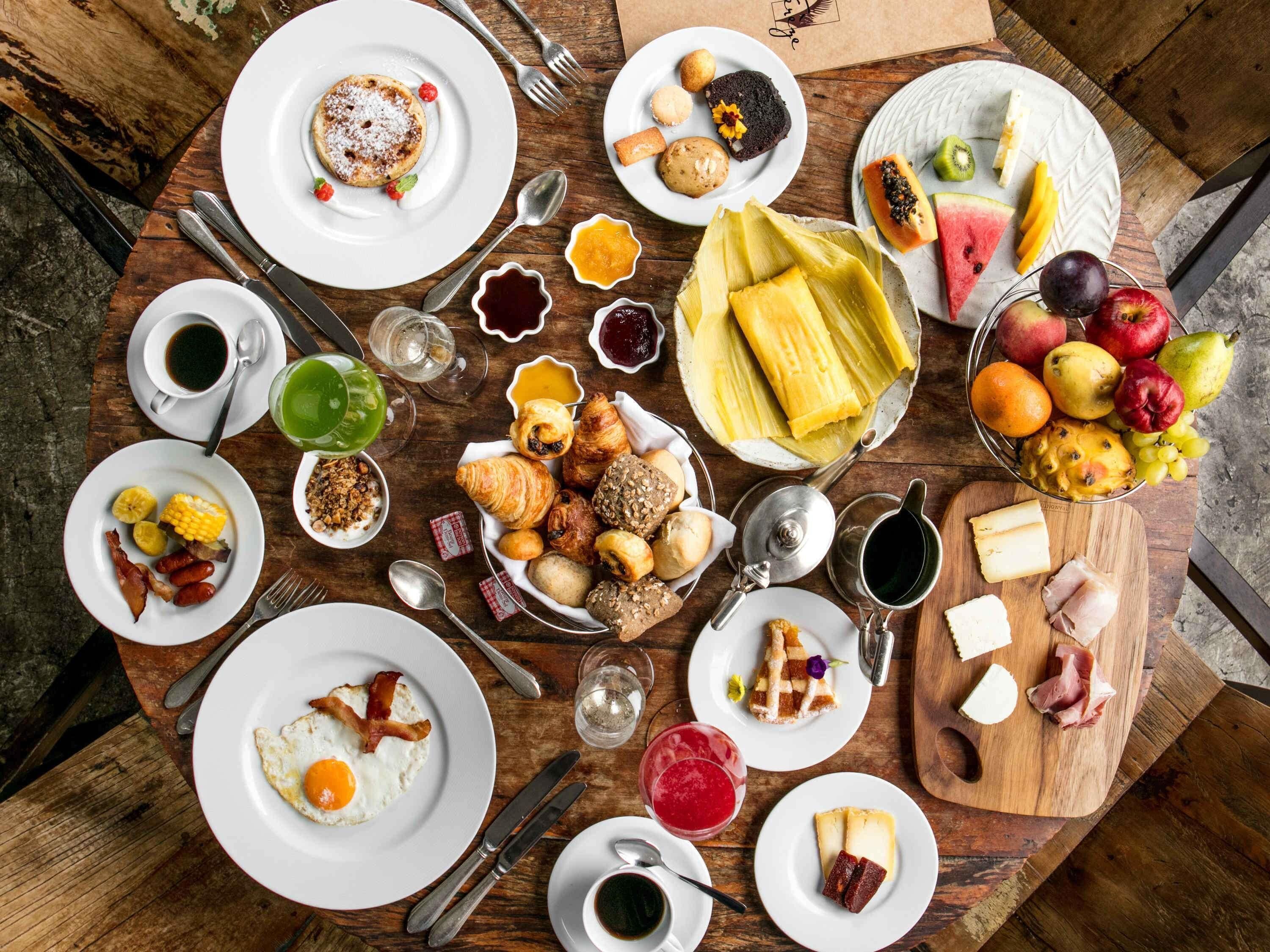 A breakfast spread with various foods and drinks on a wooden table.