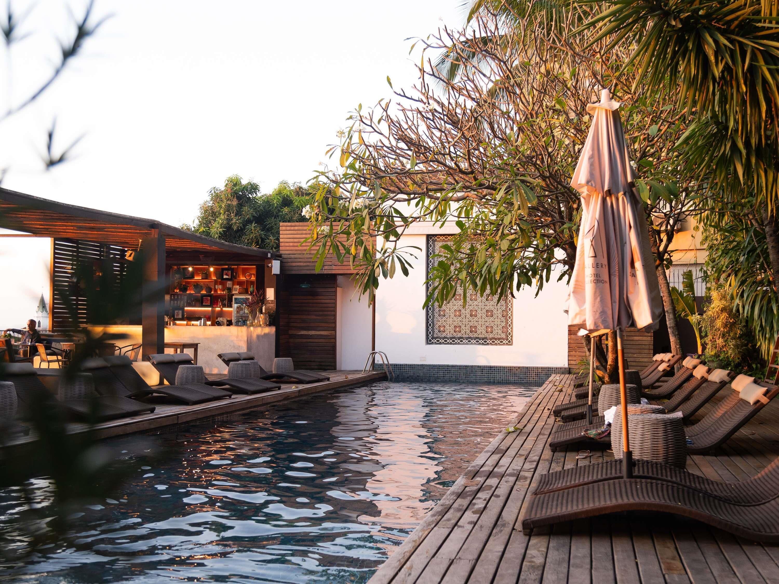 Un espace aménagé au bord de la piscine, avec des chaises longues, un bar et un mur décoré de motifs.