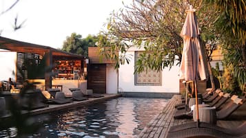 A poolside area with lounge chairs, a bar, and a patterned wall.