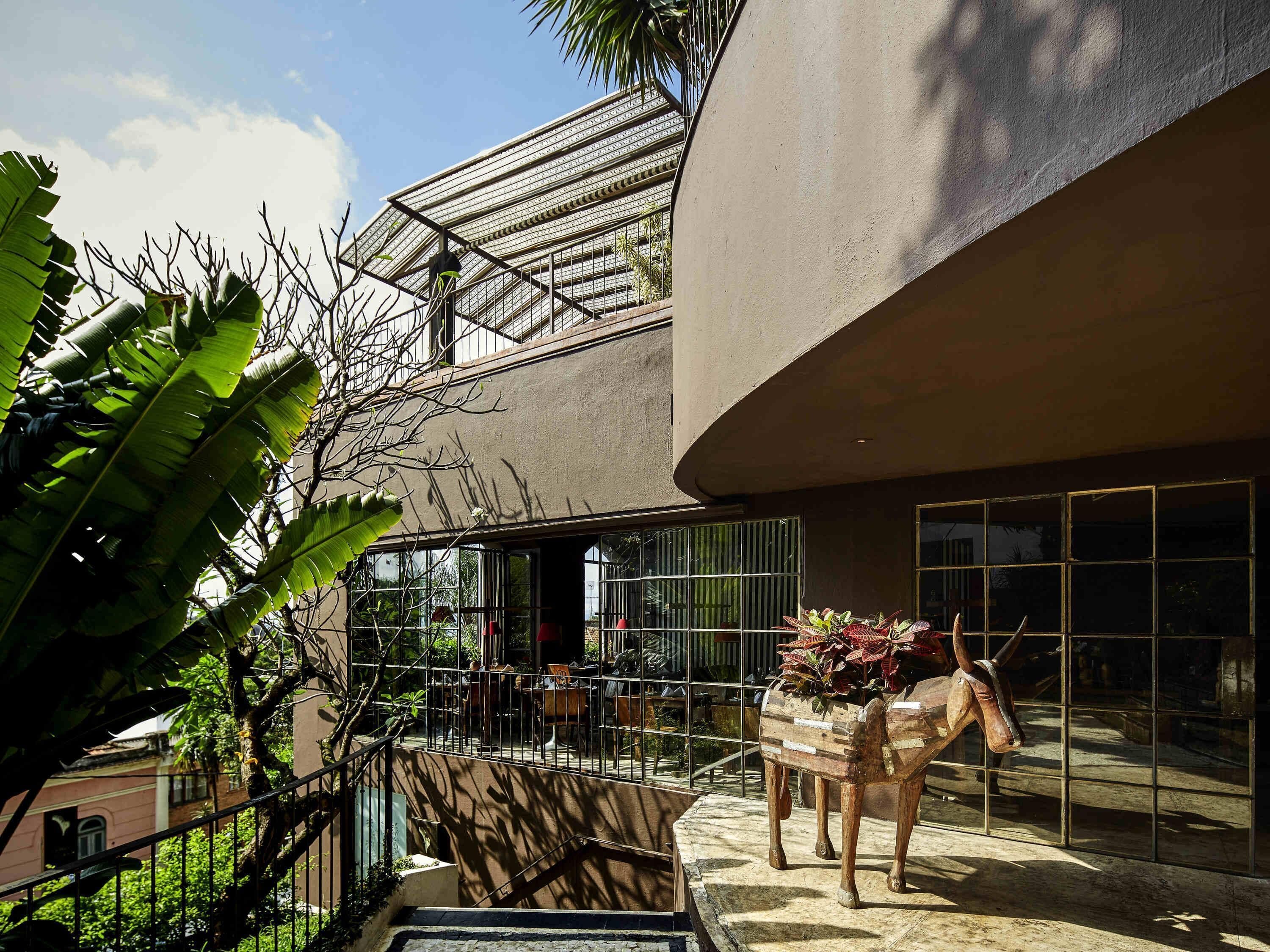 A modern building with a glass facade, a staircase, and a wooden horse sculpture.