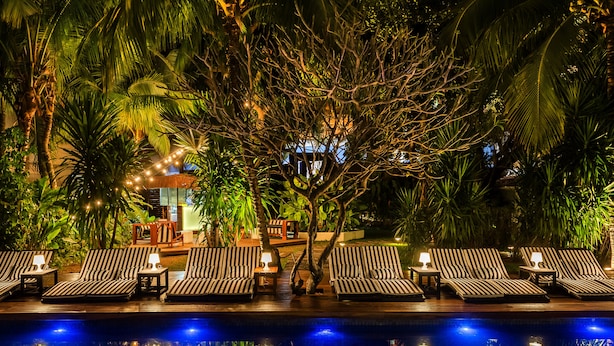 A poolside area with lounge chairs and a small table, surrounded by lush greenery and palm trees. - Santa Teresa Hotel Rio de Janeiro - MGallery Collection (Rio de Janeiro)
